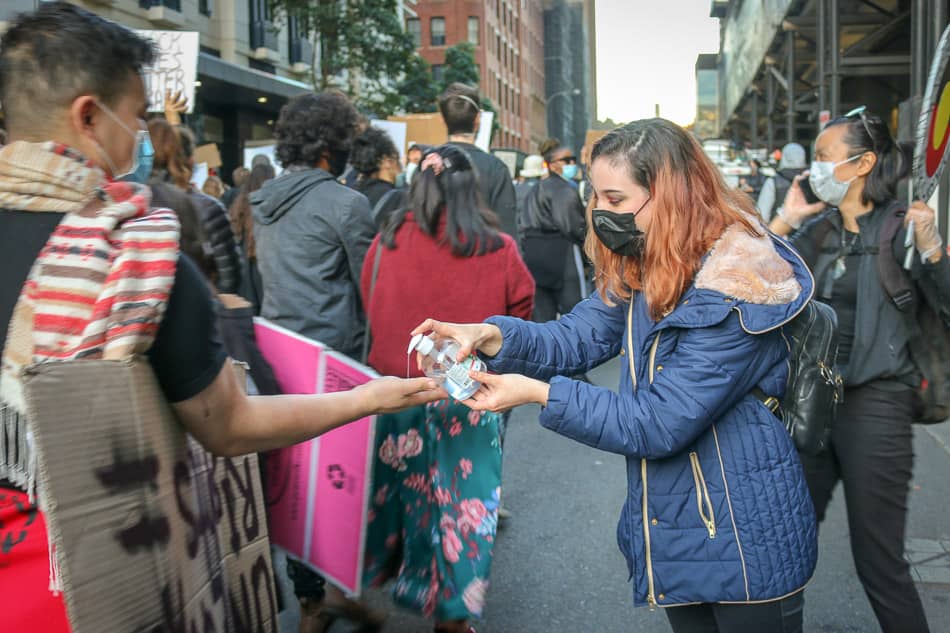 Woman squirts hand sanitiser on passer by at Sydney Black Lives Matter protest