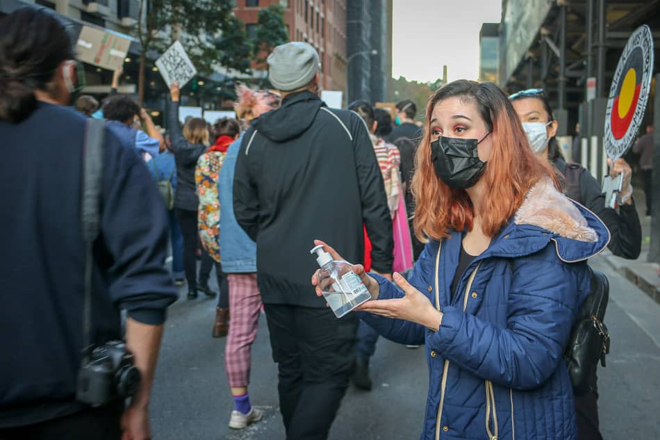 woman offers hand sanitiser at Sydney Black Lives Matter protest